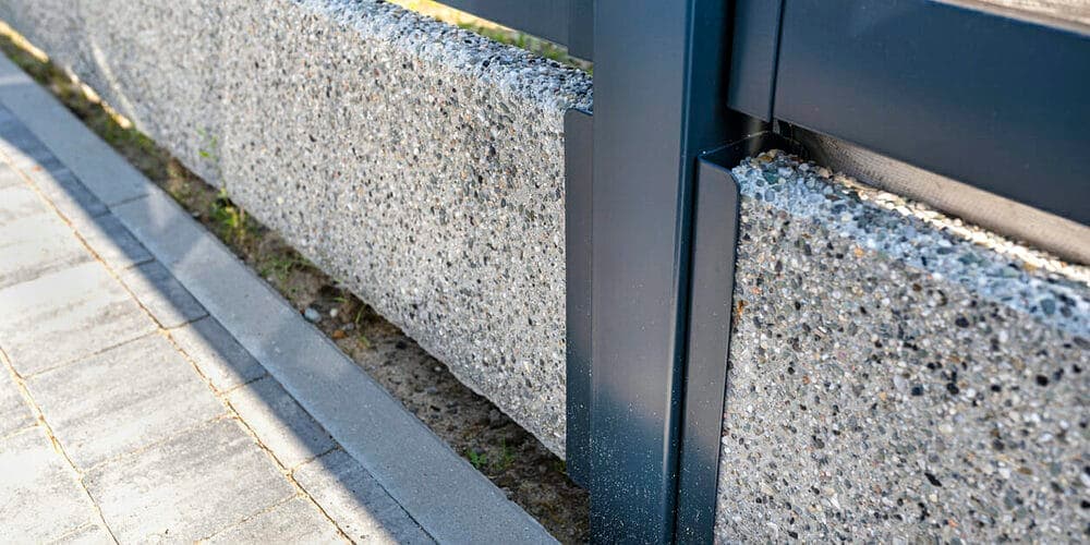 Pour concrete along the base of the fence